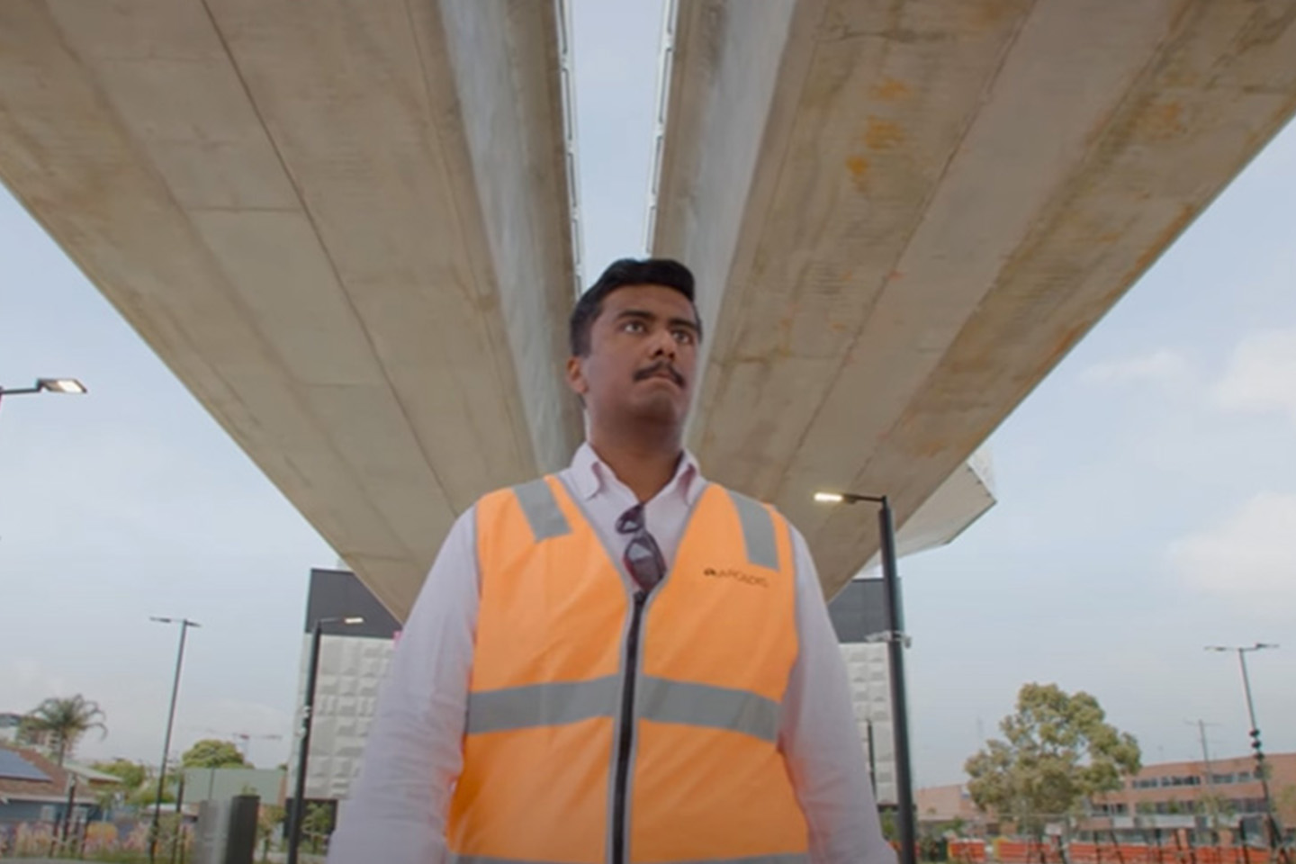 Hasan in an orange safety vest pictured under a bridge with two sections